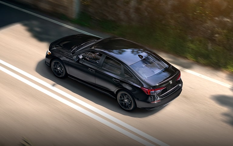 2027 Honda Civic Sedan Sport in Crystal Black Pearl high-angle rear three-quarter view driving on a road (Compact Sedan)